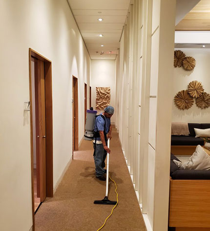 man vacuuming an apartment building hallway